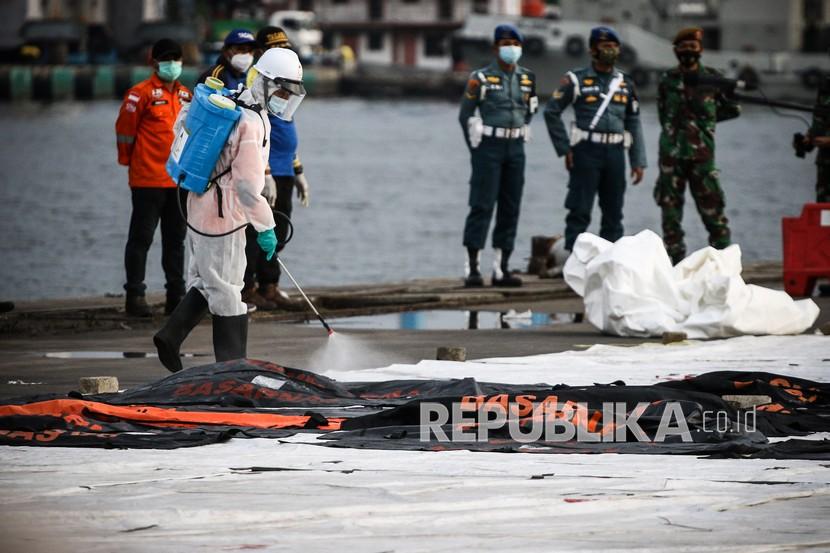 Petugas menyemprotkan cairan disinfektan pada kantong jenazah berisi objek temuan dari lokasi jatuhnya pesawat Sriwijaya Air nomor penerbangan SJ 182 rute Jakarta-Pontianak di Dermaga JICT, Tanjung Priok, Jakarta, Sabtu (16/1/2021). Operasi SAR tersebut memasuki hari kedelapan.