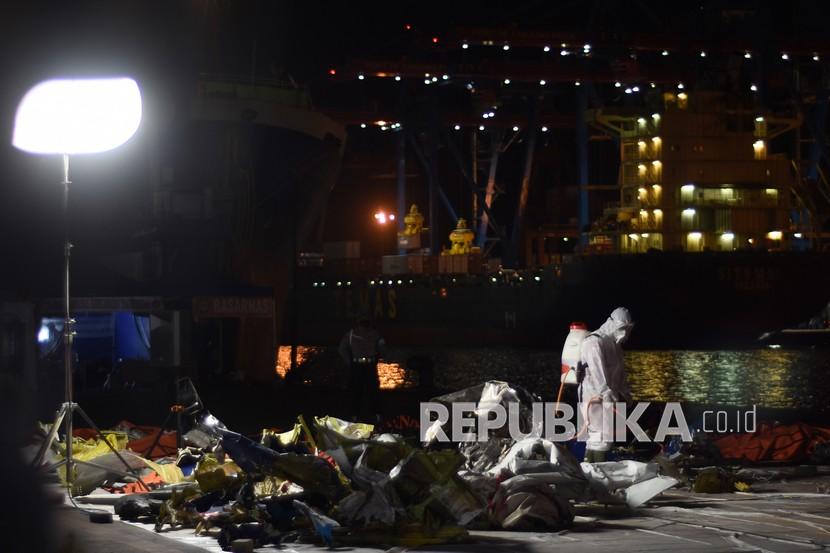 Petugas menyemprotkan cairan disinfektan pada kantong jenazah dan puing pesawat Sriwijaya Air nomor penerbangan SJ 182 rute Jakarta-Pontianak pada hari ketujuh operasi SAR pesawat tersebut di Dermaga JICT, Tanjung Priok, Jakarta Utara, Jumat (15/1/2021).
