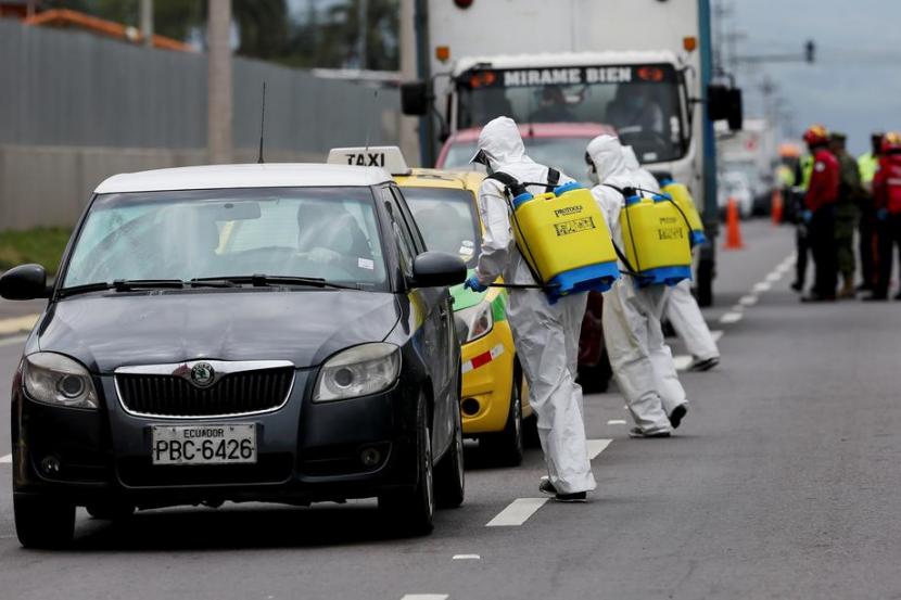 Petugas menyemprotkan disinfektan ke kendaraan yang akan masuk Kota Quito, Ekuador, Kamis (26/3). Ekuador menjadi salah satu negara terdampak Covid-19.