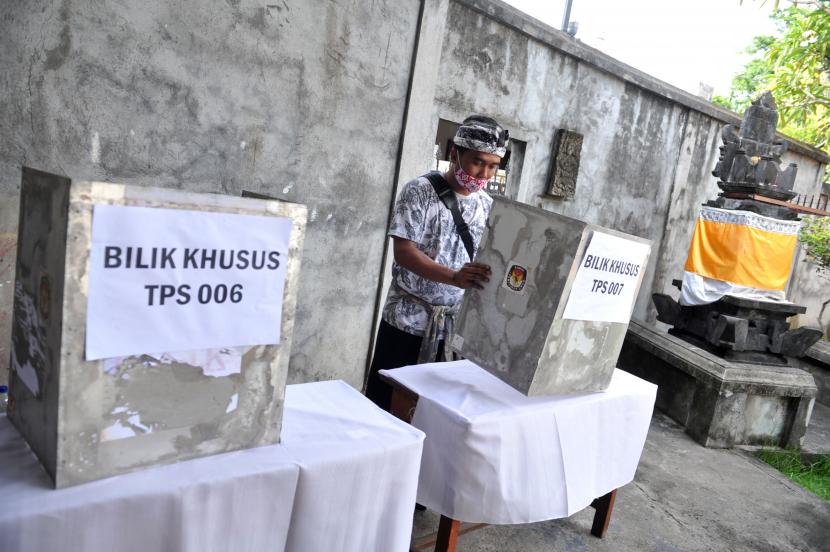 Petugas menyiapkan bilik suara khusus bagi pemilih yang bersuhu tubuh di atas batas yang ditetapkan di Tempat Pemungutan Suara (TPS) di kawasan Banjar Abian Kapas Kelod, Denpasar, Bali, Selasa (8/12/2020). Sebanyak 1.202 TPS yang tersebar di empat kecamatan se-Denpasar disiapkan untuk pelaksanaan pemungutan suara Pilkada Kota Denpasar pada 9 Desember 2020.