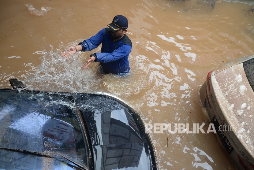  Petugas menyiram kendaraan terjebak banjir di parkir basement di Jalan Kemang Raya, Jakarta, Ahad (28/8)(Republika/Wihdan)
