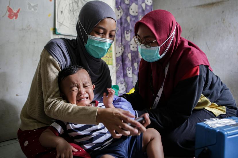 Petugas menyuntikkan vaksin campak kepada seorang anak saat imunisasi door to door dalam rangka Bulan Imunisasi Anak Nasional di Sukasari, Kota Tangerang, Banten, Sabtu (13/8/2022).