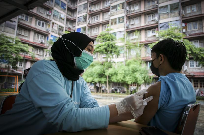 Petugas menyuntikkan vaksin COVID-19 dosis ketiga alias booster kepada warga di RPTRA Rusun Benhil, Jakarta. Epidemiolog menilai kebijakan vaksin booster jadi syarat perjalanan sangat tepat.