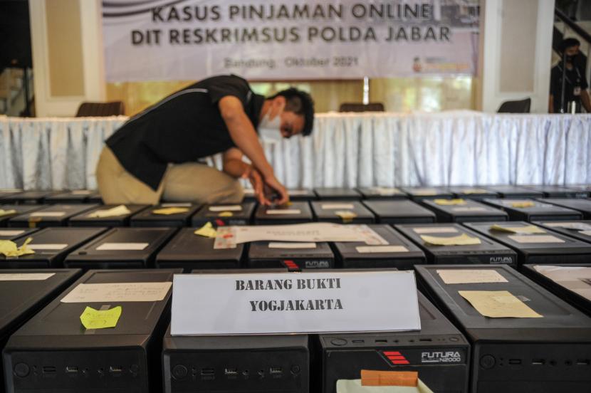 Petugas merapikan barang bukti berupa perangkat komputer saat konferensi pers pengungkapan kasus pinjaman online di Polda Jabar, Bandung, Jawa Barat, Kamis (21/10). 