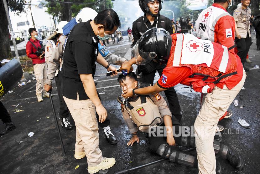 Petugas Palang Merah Indonesia (PMI) Kota Bandung mengevakuasi petugas kepolisian yang terkena gas air mata saat Aksi Tolak RUU Bermasalah di Jalan Diponegoro, Kota Bandung.