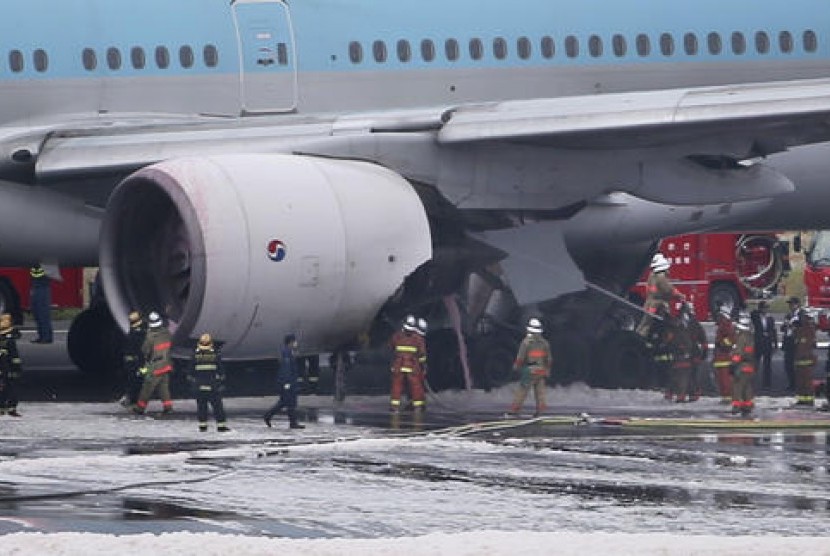 Petugas pemadam kebakaran bekerja memadamkan mesin pesawat Korean Air yang terbakar di Bandara Haneda, Tokyo, Jumat, 27 Mei 2016.
