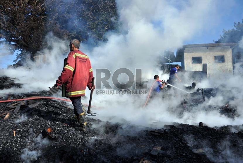  Petugas pemadam kebakaran berada di antara kepulan asap bekas api yang membakar gudang kayu dan bengkel mebel di Cimanggis, Depok, Jawa Barat, Senin (18/3).  (Republika/Rakhmawaty La'lang)