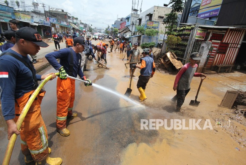 Petugas pemadam kebakaran bersama warga bergotong-royong membersihkan lumpur sisa banjir bandang yang memenuhi Jalan di kawasan Cicaheum, Kota Bandung, Rabu (21/3).