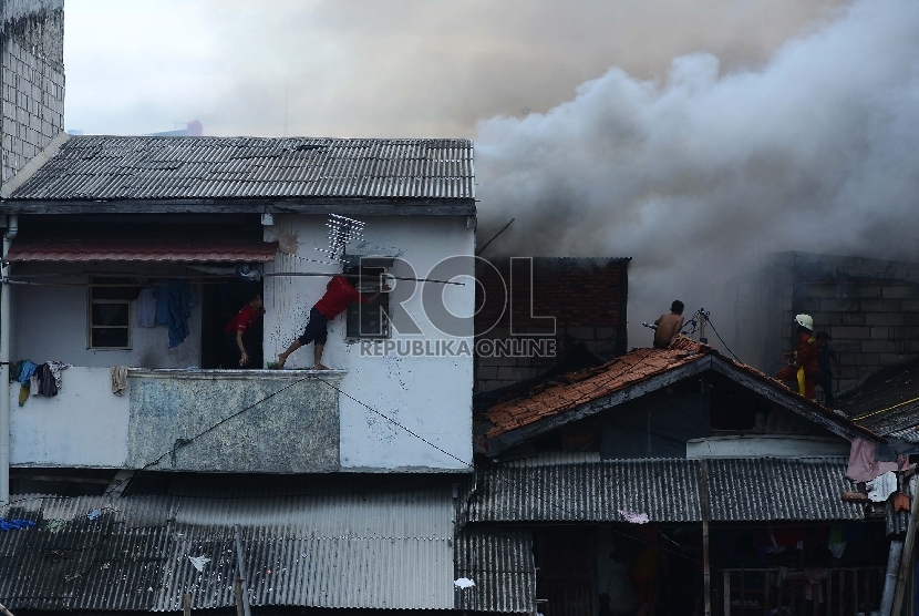  Petugas pemadam kebakaran bersama warga berusaha untuk memadamkan api yang membakar salah satu rumah di Kawasan Kebon Pala