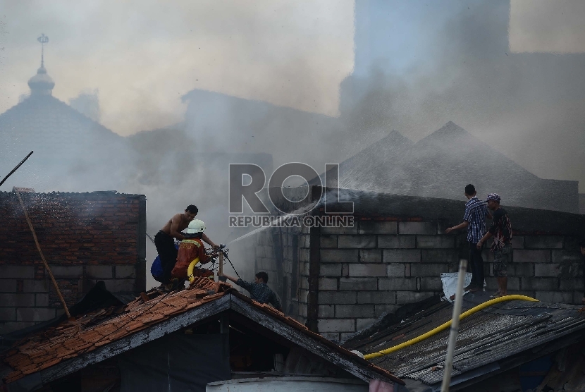Petugas pemadam kebakaran bersama warga berusaha untuk memadamkan api yang membakar salah satu rumah di Kawasan Kebon Pala, Penjaringan, Jakarta Utara, Rabu (11/3).  (Republika/Raisan Al Farisi)