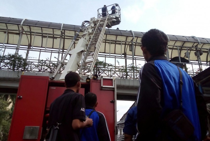 Petugas pemadam kebakaran berupaya menyelamatkan seorang pria yang ingin melakukan bunuh diri dari atap Jembatan Penyeberangan Orang (JPO) di depan Gedung Bank Indonesia, Jln MH Thamrin, Sabtu (25/3).