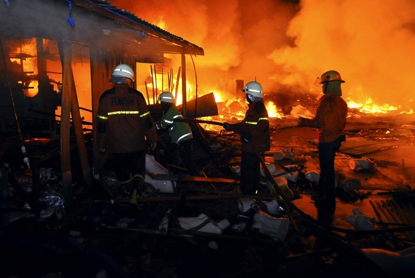 Petugas pemadam kebakaran berusaha memadamkan api yang membakar kios pedagang di Pasar Cik Puan, Kota Pekanbaru, Riau, Senin malam (6/7).