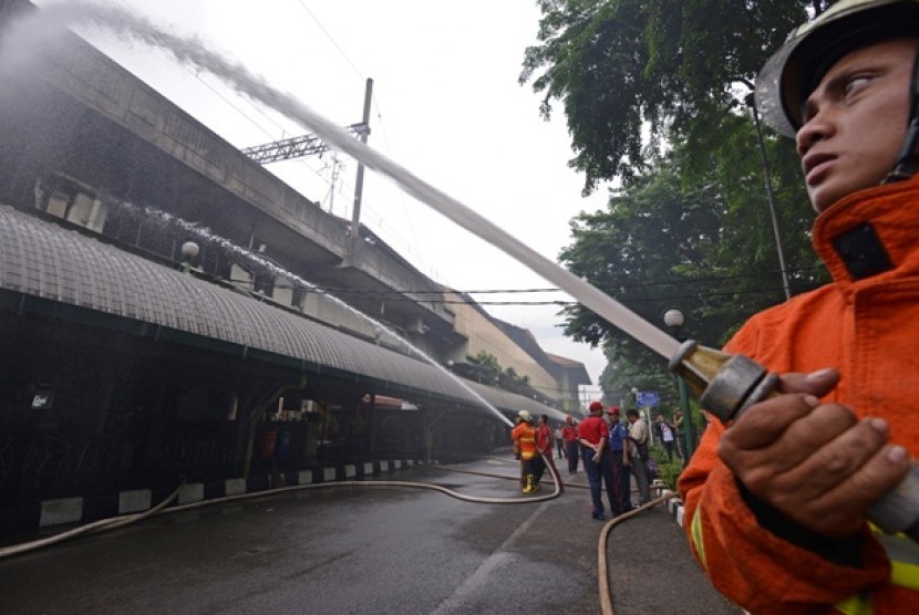 Petugas pemadam kebakaran berusaha memadamkan api yang membakar sebuah restoran cepat saji di Stasiun Gambir, Jakarta Pusat, Jumat (27/12). 