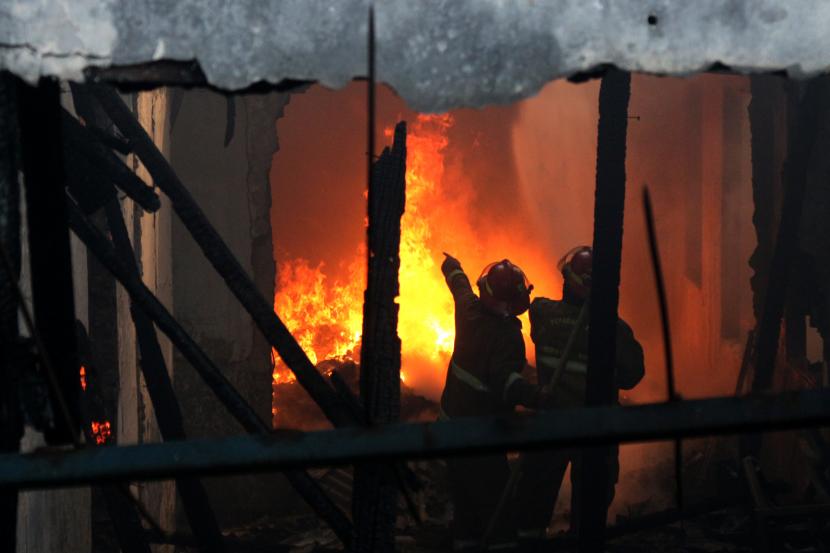 Petugas pemadam kebakaran berusaha memadamkan api yang membakar sebuah pabrik. 