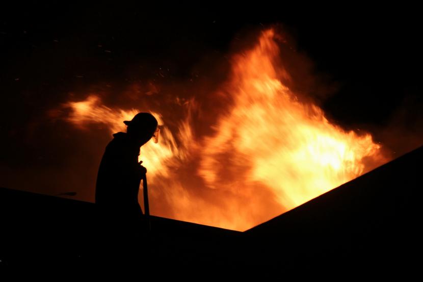 Petugas pemadam kebakaran berusaha memadamkan api saat permukiman warga terbakar.