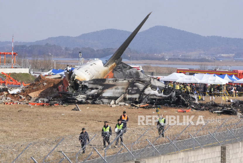 Petugas pemadam kebakaran dan anggota tim penyelamat bekerja di landasan pacu Bandara Internasional Muan di Muan, Korea Selatan, Ahad, 29 Desember 2024 untuk menyelamatkan dan mengevakuasi penumpang pesawat Boeing 737-800 milik Maskapai Jeju Air yang terbakar dan meledak setelah menabrak dinding usai mendarat.