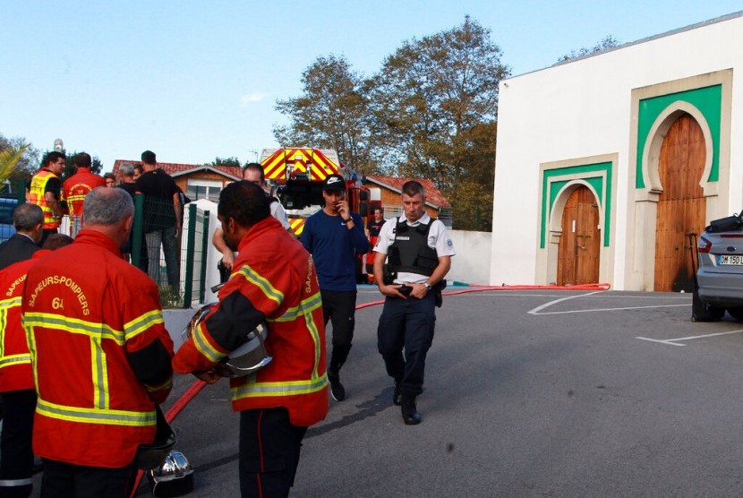 Petugas pemadam kebakaran dan polisi berjaga di luar masjid di Bayonne, Prancis setelah penembakan dan pembakaran masjid, Senin (28/10).