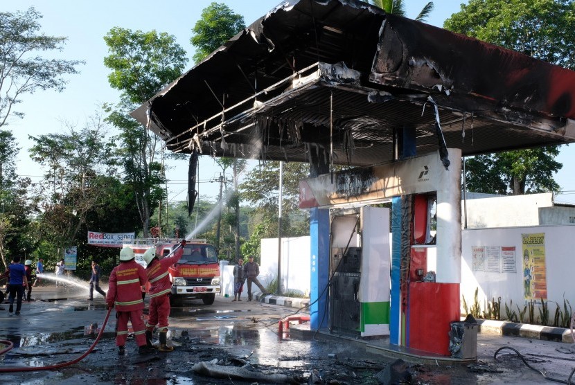 Petugas pemadam kebakaran dibantu warga berusaha memadamkan api yang membakar mobil di Stasiun Pengisian Bahan Bakar Umum (SPBU). ilustrasi