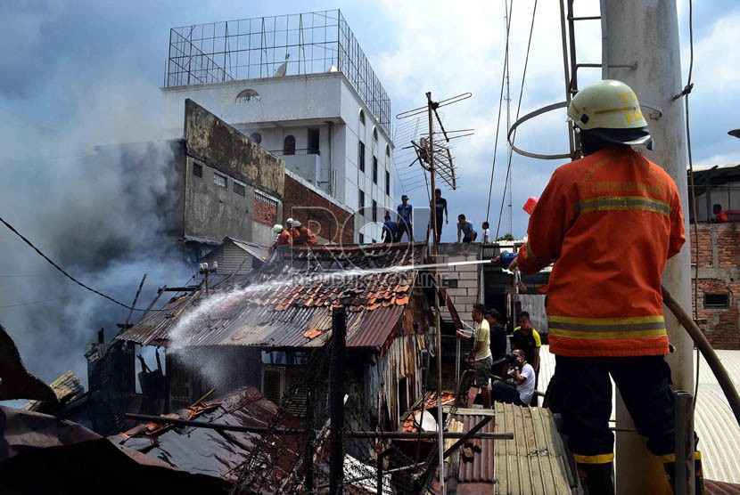  Petugas Pemadam kebakaran dibantu warga berusaha memadamkan rumah yang terbakar di Jalan Salemba, Senen, Jakarta Pusat, Selasa (12/3).   (Republika/ Agung Supriyanto)