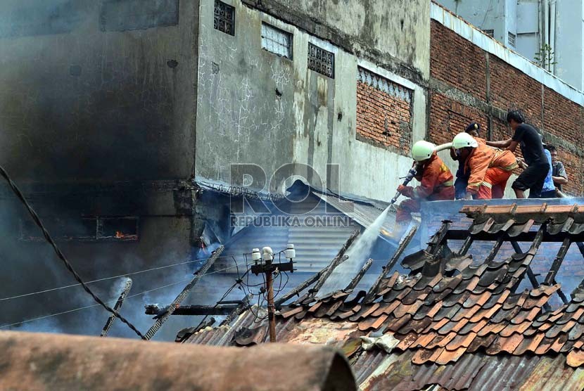  Petugas Pemadam kebakaran dibantu warga berusaha memadamkan rumah yang terbakar di Jalan Salemba, Senen, Jakarta Pusat, Selasa (12/3).   (Republika/ Agung Supriyanto)