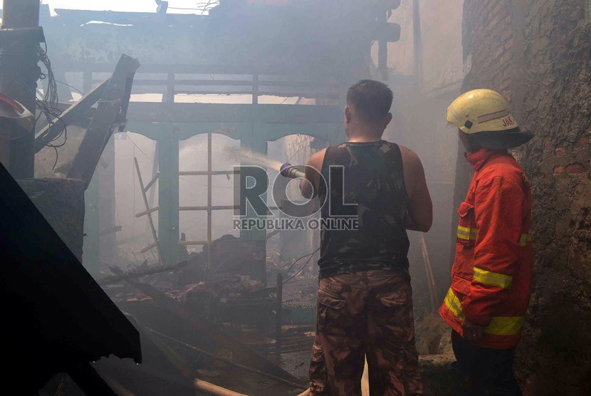  Petugas Pemadam kebakaran dibantu warga berusaha memadamkan rumah yang terbakar di Jalan Salemba, Senen, Jakarta Pusat, Selasa (12/3).   (Republika/ Agung Supriyanto)