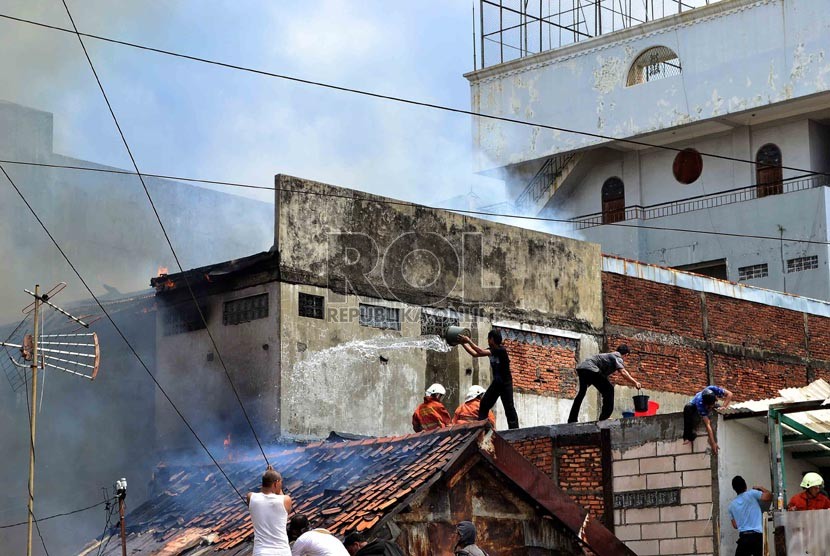  Petugas Pemadam kebakaran dibantu warga berusaha memadamkan rumah yang terbakar di Jalan Salemba, Senen, Jakarta Pusat, Selasa (12/3).   (Republika/ Agung Supriyanto)