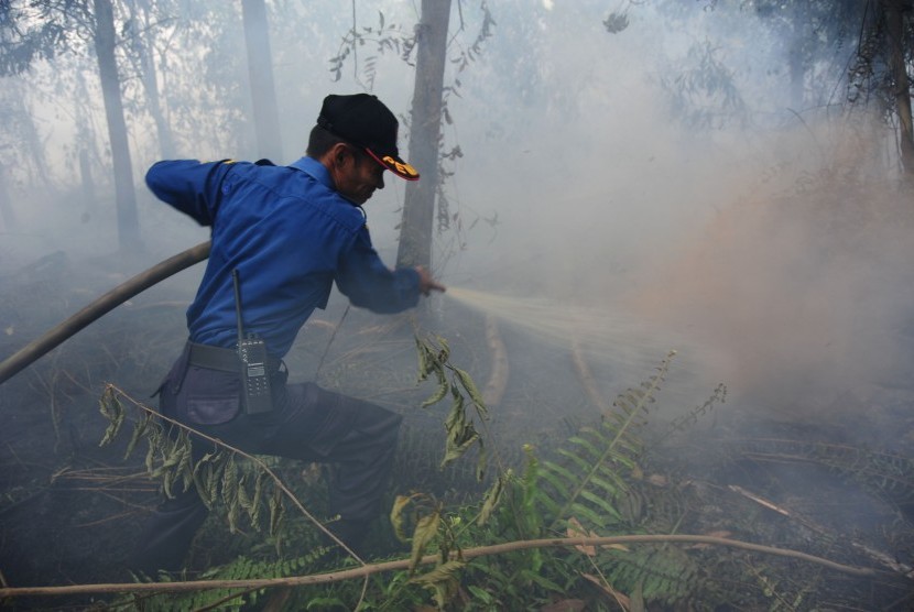 Petugas pemadam kebakaran Kota Pontianak memadamkan api yang merambat di bawah tanah lahan gambut di Jalan Parit Haji Husin II, Pontianak, Kalbar, Senin (22/8). 