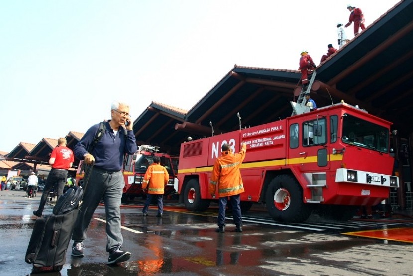 Petugas pemadam kebakaran melakukan pendinginan Gate 3 keberangkatan Luar Negeri yang terbakar di Terminal 2E Bandara Soekarno Hatta, Tangerang, Banten, Minggu (5/7). Kebakaran yang menghanguskan ruang tunggu Terminal 2E masih dalam penyelidikan pihak berw