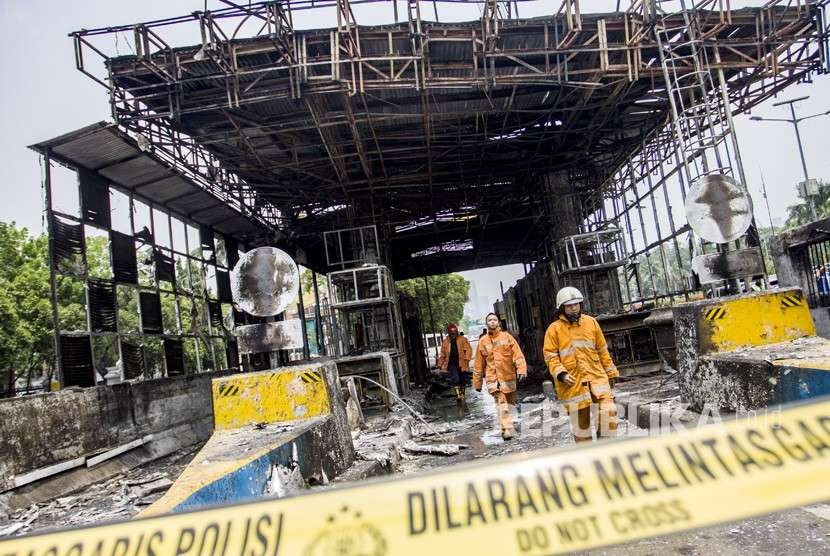 Petugas pemadam kebakaran memeriksa bangunan yang terbakar usai dipadamkan di Gardu Tol Pejompongan, Jakarta, Kamis (27/9).