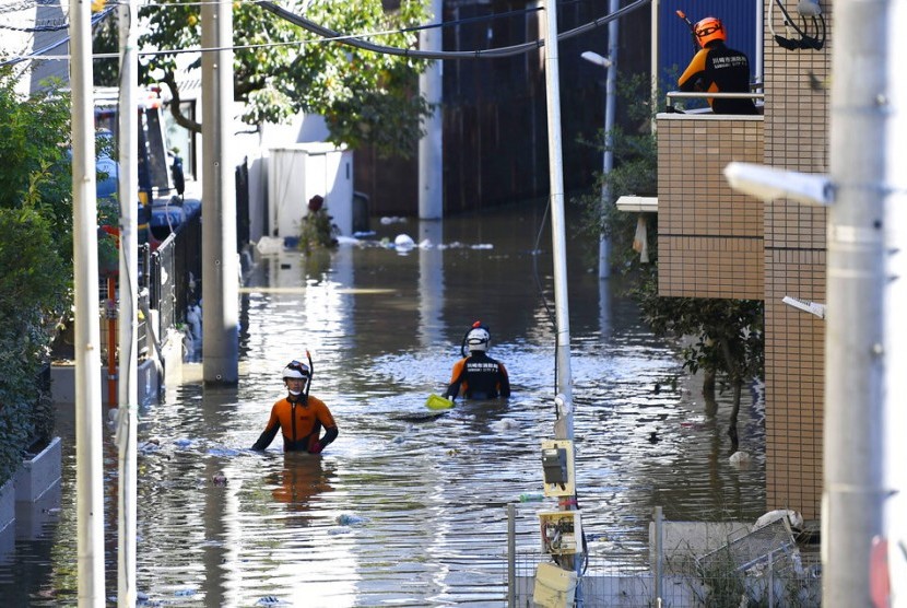 Petugas pemadam kebakaran memeriksa kawasan yang dilanda banjir akibat Topan Hagibis di Kawasaki, dekat Tokyo, Jepang, Ahad (13/10).
