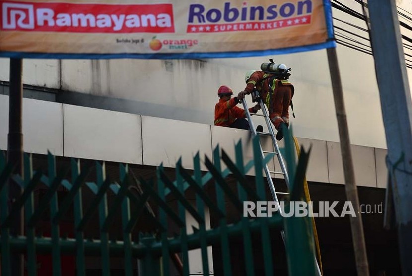 Petugas Pemadam Kebakaran menaiki tangga menuju balkon untuk memadamkan api di Gedung Toserba Ramayana Pasar Minggu yang terbakar Kamis (18/5). 