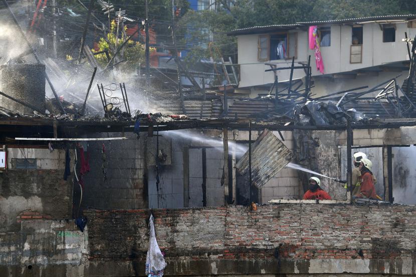 Petugas pemadam kebakaran mendinginkan sisa bangunan yang terbakar di kawasan Bendungan Hilir, Jakarta Pusat.