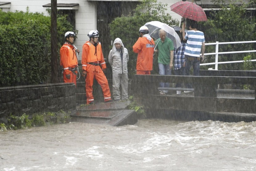 Petugas pemadam kebakaran mengawasi tingkat air di Sungai Wada saat hujan lebat melanda Kagoshima City, Jepang, Rabu (3/7).