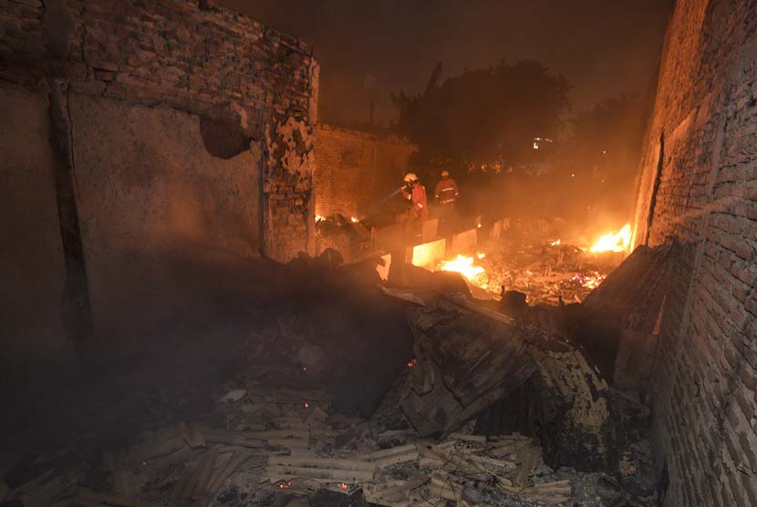 Petugas pemadam kebakaran mengecek sisa bangunan yang terbakar di Kelurahan Jembatan Besi, Tambora, Jakarta Barat, Sabtu (26/9) malam. 