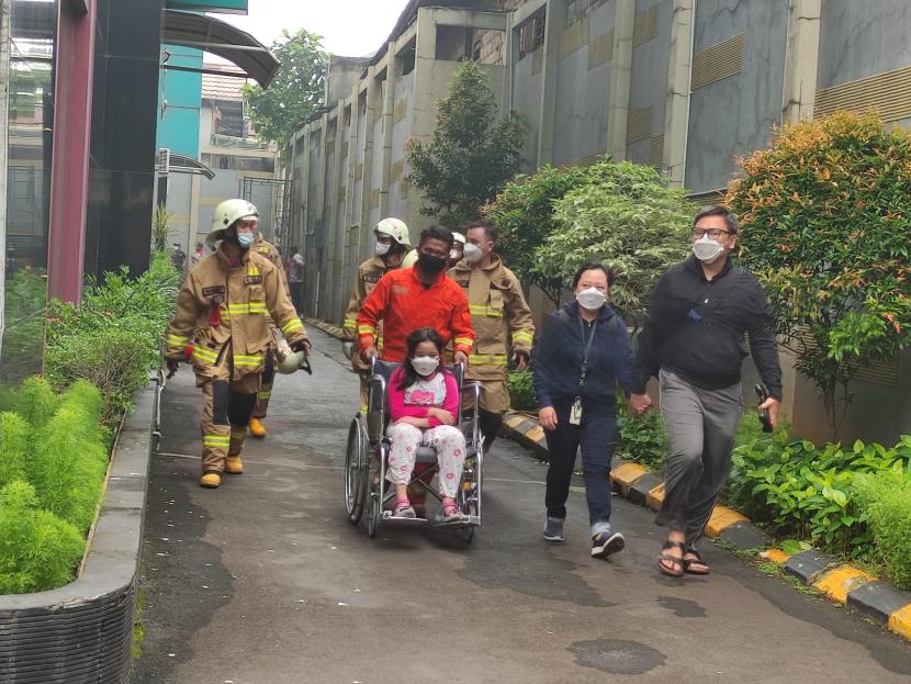 Petugas pemadam kebakaran mengevakuasi penghuni Apartemen Taman Sari, Setiabudi, Jakarta Selatan, saat kebakaran terjadi di bagian basemen apartemen pada Ahad (4/4) dini hari. 