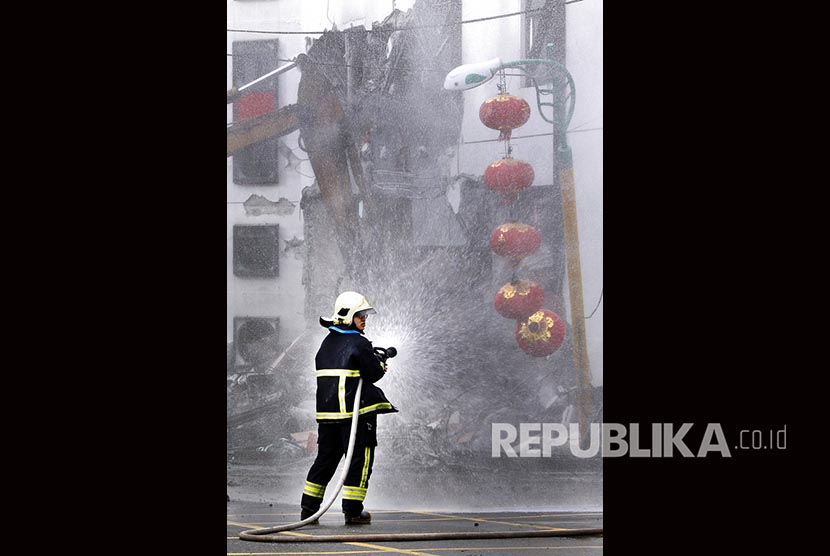 Petugas pemadam kebakaran menyemprotakan air di tengah upaya evakuasi korban gempa di Hualien, Taiwan Timur.