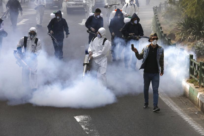 Petugas pemadam kebakaran menyemprotkan disinfektan virus corona di alun-alun di barat Teheran, Iran, Jumat, 13 Maret 2020.
