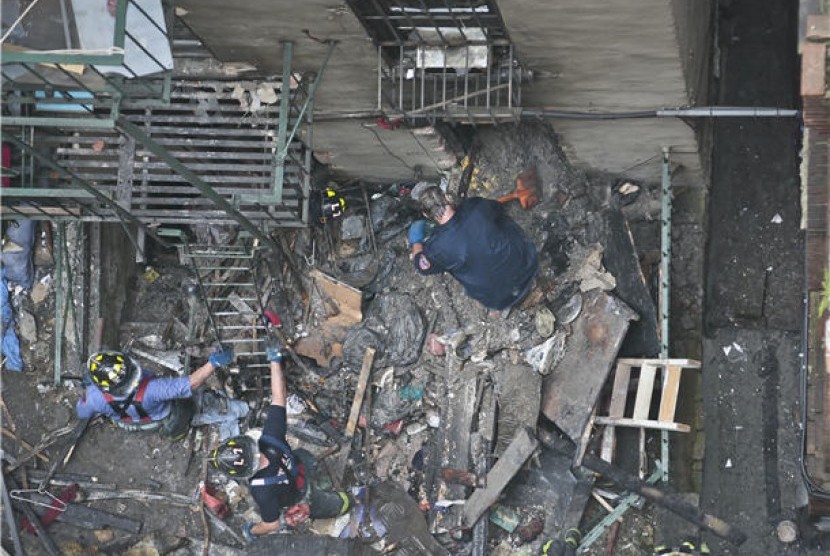 Petugas pemadam kebakaran menyingkirkan runtuhan bangunan setelah kebakaran melanda kawasan Chinatown di Manhattan, New York, Amerika Serikat, Kamis (11/7). 