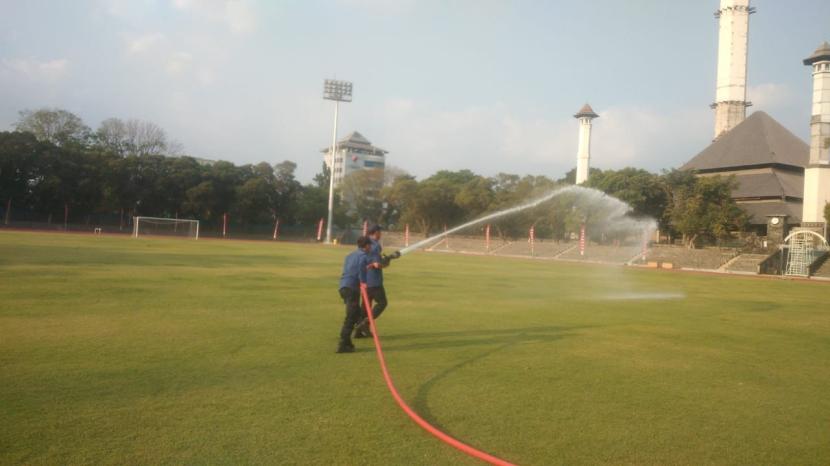 Petugas pemadam kebakaran menyiram rumput di Stadion Sriwedari Solo, Senin (21/8/2023).