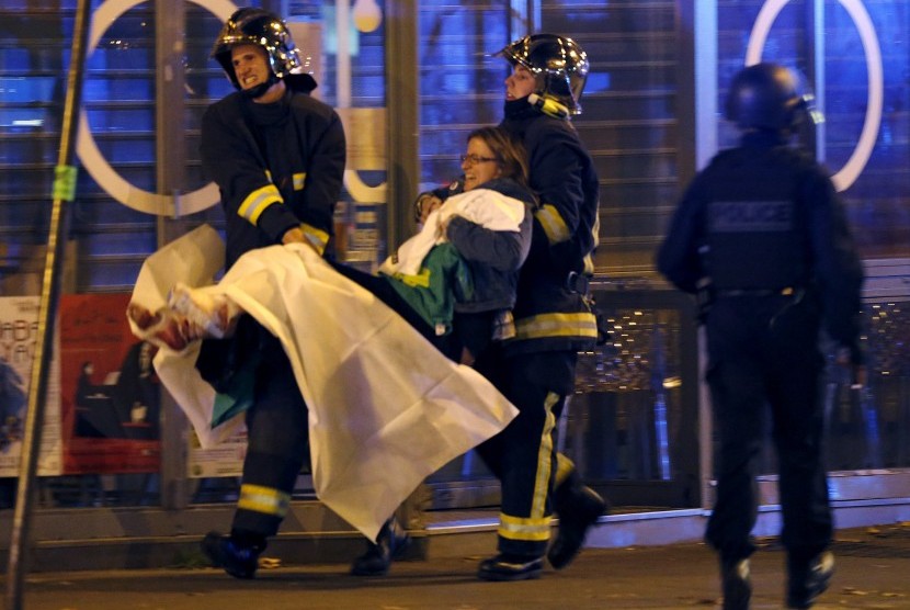 Petugas pemadam kebakaran Prancis menolong seorang korban akibat aksi teror di dekat Bataclan Concert Hall, Jumat malam waktu Paris (13/11).