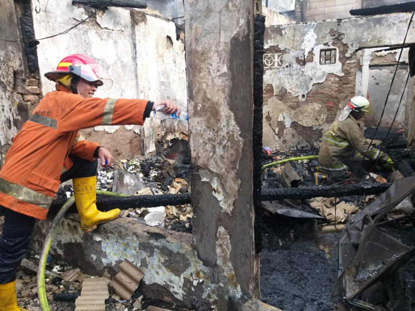 Petugas pemadam kebakaran sedang melakukan proses pendinginan di sebuah rumah yang terbakar di Jalan Penegak I, Kelurahan Palmeriah, Matraman, Jakarta Timur, Jumat (26/3) siang.