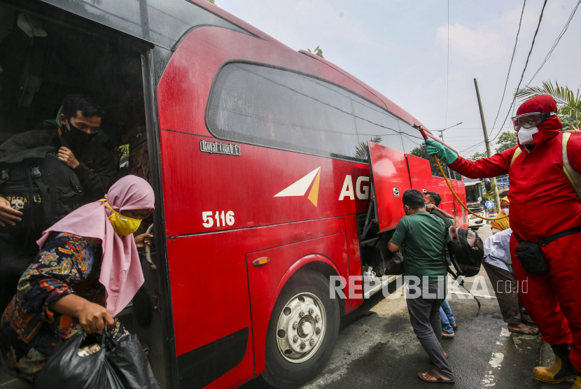 Petugas pemadam menyemprotkan cairan disinfektan kepada pemudik yang baru tiba di Terminal Kampung Rambutan, Jakarta, Rabu (19/5/2021).