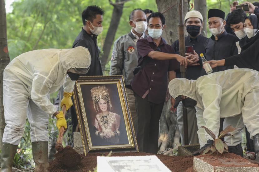 Petugas pemakaman memakamkan jenazah artis senior Dorce Gamalama dengan protokol COVID-19 di TPU Bantar Jati, Cipayung, Jakarta, Rabu (16/2/2022). Dorce Gamalama meninggal dunia pada usia 59 tahun akibat infeksi virus COVID-19.