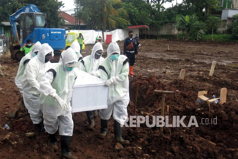 Petugas pemakaman membawa peti jenazah korban Covid-19.