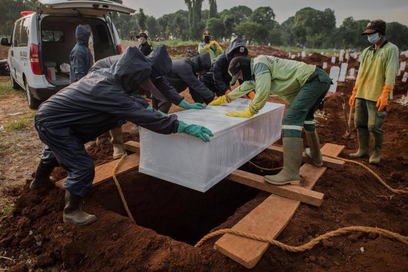 Petugas pemakaman menguburkan jenazah dengan protokol COVID-19 di TPU Pondok Ranggon, Jakarta.