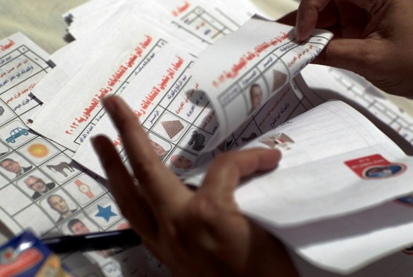  Petugas pemilu menghitung kertas suara yang berisi foto calon presiden di tempat pemungutan suara di Kairo, Mesir, Kamis (24/5).  (Fredrik Persson/AP) 