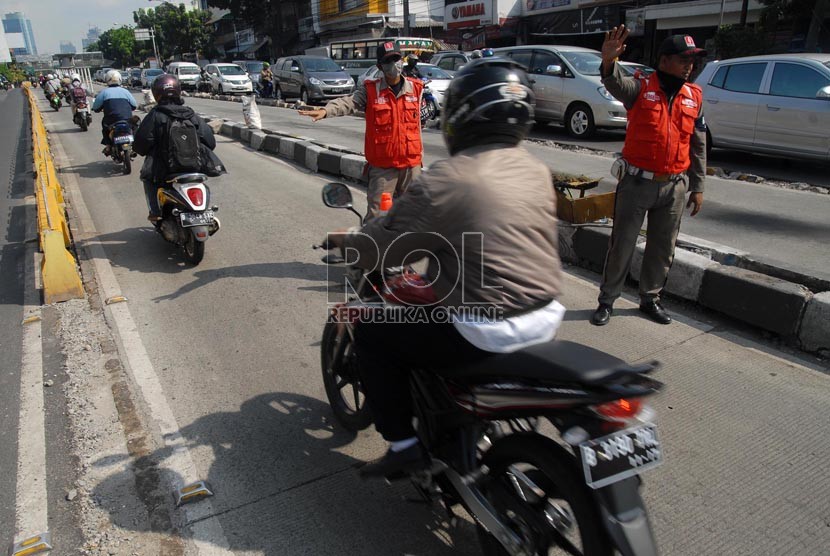   Petugas penjaga jalur busway menghalau sejumlah pengendara kendaraan bermotor yang hendak melintasi jalur busway di jalan Warung Buncit, Jakarta Selatan, Rabu (28/11).  (Republika/Agung Fatma Putra)