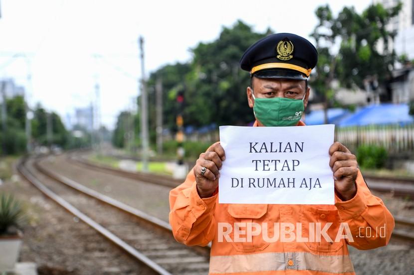 Petugas penjaga palang pintu kereta api Dedi (44) menunjukan pesan untuk tetap di rumah dari tempat kerjanya di Jakarta, Sabtu (4/4/2020). Sejumlah warga masih melakukan aktivitas kerja di luar rumah seperti biasanya meski di saat pandemi COVID-19 agar tetap memberikan pelayanan kepada warga.
