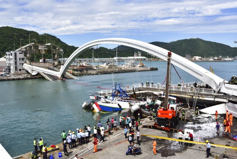 Petugas penyelamat bekerja di lokasi ambruknya jembatan di sebuah pelabuhan di Nanfangao, timur Taiwan, Selasa (1/10). Jembatan ambruk ketika sebuah truk tanker melintas dan menimpa sebuah kapal di bawahnya. 