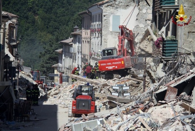 Petugas penyelamat bekerja di sebuah rumah ambruk setelah gempa di Amatrice, Italia Tengah, Jumat (26/8).